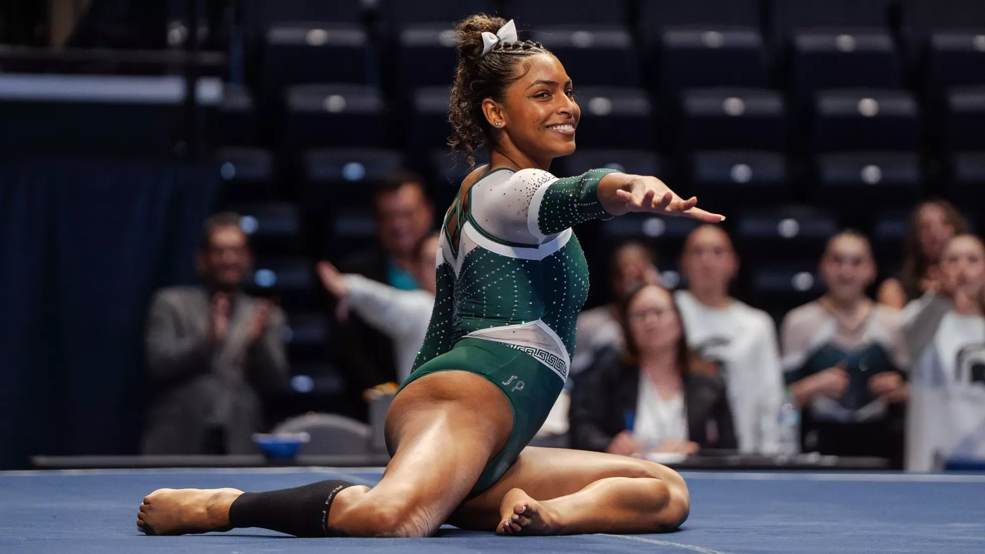 MaKayla Tucker smiling and posing on the floor exercise mat in her Michigan State leotard